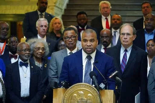 Hinds County District Attorney Jody Owens, center, stands with Lt. Gov. Delbert Hosemann, right, and a delegation of Hinds County legislators, supervisors, lawmen, and U.S. Rep. Michael Guest, R-Miss., and speaks to reporters about the Hinds County Public Safety Initiative, a project they believe will address crime in Hinds County through temporary judges, assistant district attorneys, and public defenders, Wednesday, May 4, 2022, in Jackson, Miss. (AP Photo/Rogelio V. Solis)