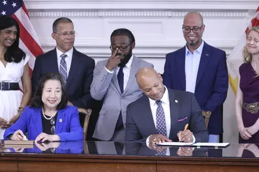 Maryland Gov. Wes Moore signs an executive order to issue more than 175,000 pardons for marijuana convictions on Monday, June 17, 2024 in Annapolis, Md. Maryland Secretary of State Susan Lee is seated left. Standing left to right are Lt. Gov. Aruna Miller, Maryland Attorney General Anthony Brown, Shiloh Jordan, Jason Ortiz, director of strategic initiatives for Last Prisoner Project and Heather Warnken, executive director of the University of Baltimore School of Law Center for Criminal Justice. 