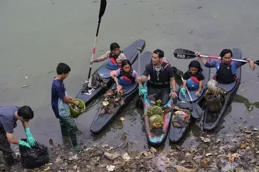 Environmental activist members of the Situ Gede Cleanliness Warrior pick up trash while paddling kayaks at Setu Gede lake in Bogor, West Java, Indonesia, Tuesday, Oct. 10, 2023. Young people have been at the forefront of environmental and climate change movements in recent years: initiatives like school strikes for climate action, protests at United Nations climate talks and around the world, and local clean ups have often been youth-led. (AP Photo/Achmad Ibrahim)