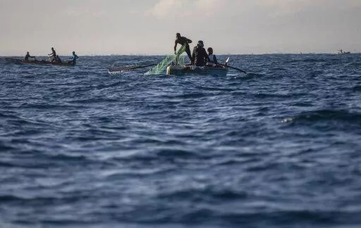 A fisherman pulls his net back onto his boat in the waters surrounding Cap-Haitien, Haiti, Friday, March 11, 2022. A prize winning marine biologist is working to bring together fishermen from Haiti and the Dominican Republic and find a solution that will not only save their livelihoods but also vital marine resources in a region under extreme pressures from climate change. (AP Photo/Odelyn Joseph)