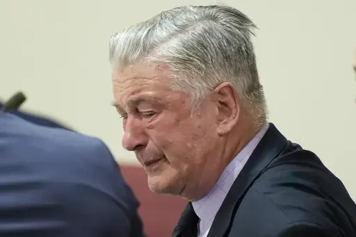 Actor Alec Baldwin, center, reacts as he sits between his attorneys Alex Spiro, left, and Luke Nikas after the judge threw out the involuntary manslaughter case for the 2021 fatal shooting of cinematographer Halyna Hutchins during filming of the Western movie "Rust," Friday, July 12, 2024, in Santa Fe, N.M. (Ramsay de Give/Pool Photo via AP, File)