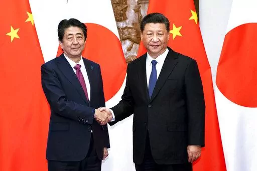 In this photo released by Xinhua News Agency, Japanese Prime Minister Shinzo Abe, left, shakes hands with Chinese President Xi Jinping as they pose for photographers before a meeting at the Diaoyutai State Guesthouse in Beijing on Oct. 26, 2018. Thursday, Sept. 29, 2022, marks the 50th anniversary of the historic communique that former Japanese Prime Minister Kakuei Tanaka signed with former Chinese Premier Zhou Enlai. (Li Tao/Xinhua via AP, File)