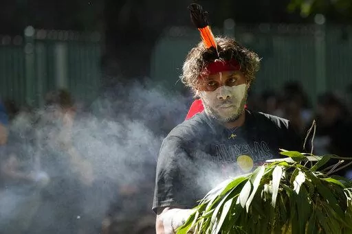 An Aboriginal man carries a smoldering fire during a smoking ceremony at the start of an Invasion Day rally in Sydney, Thursday, Jan. 26, 2023. Australia is marking the anniversary of British colonists settling modern day Sydney in 1788 while Indigenous protesters deride Australia Day as Invasion Day. (AP Photo/Rick Rycroft)