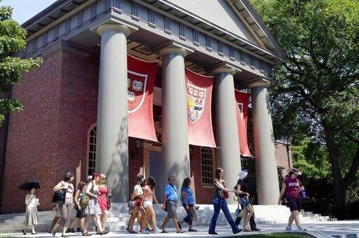 A tour group walks through the campus of Harvard University in Cambridge, Mass., Aug. 30, 2012. Harvard University is vowing to spend $100 million dollars to research and atone for its extensive ties with slavery, the school's president announced Tuesday, April 26, 2022, with plans to identify and support direct descendants of dozens of enslaved people who labored at the Ivy League campus. (AP Photo/Elise Amendola, File)