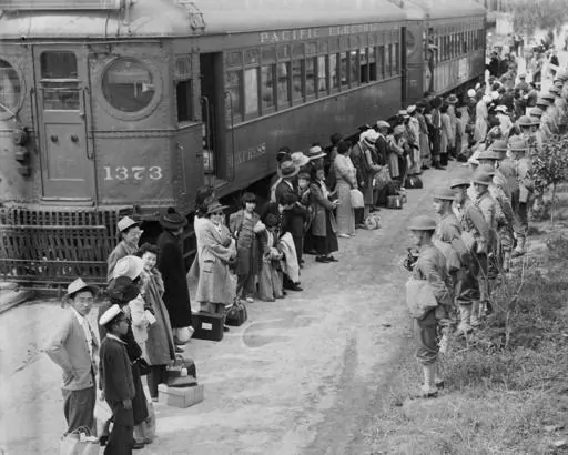 In this photo provided by the National Archives, Japanese Americans from San Pedro, Calif., arrive at the Santa Anita Assembly Center in Arcadia, Calif., on April 5, 1942. People were temporarily housed at this center at the Santa Anita race track before being moved inland to internment camps during World War II. (Clem Albers/War Relocation Authority/National Archives via AP)