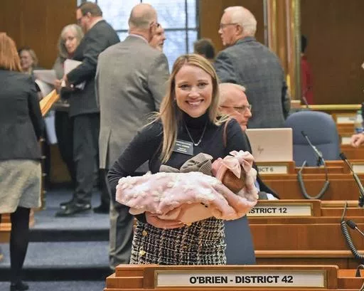 Rep. Emily O'Brien R-Grand Forks carries daughter Jolene Green, 3 weeks, into the House chamber, Dec. 6, 2022, in Bismarck, N.D. Last year, the state representative helped persuade her colleagues to approve $66 million in child care spending proposed by Gov. Doug Burnum, a Republican. O'Brien argued it could help the state's workforce shortage by helping more parents go to work. (Tom Stromme/The Bismarck Tribune via AP)