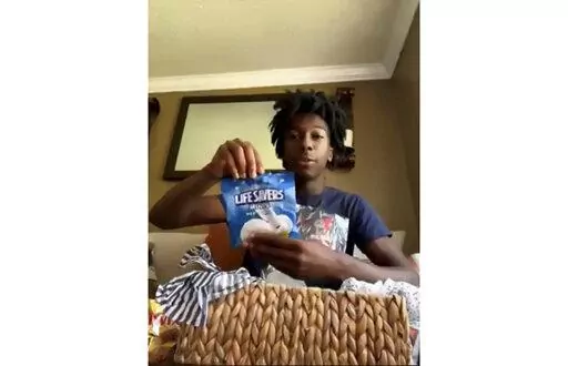 CORRECTS FIRST NAME TO CORION INSTEAD OF ORION - During a Zoom call, Friday, July 8, 2022, Corion Evans poses with candy gifted to him from the motorists he saved after their car drove off the Interstate 10 boat launch and into the Pascagoula River, in Mississippi, early Sunday, July 3. (AP Photo/Carrie Antlfinger)