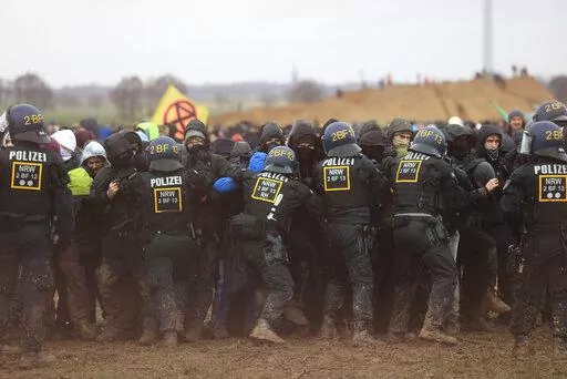 Police officers push back demonstrators on the edge of the opencast lignite mine Garzweiler at the village Luetzerath near Erkelenz, Germany, Saturday, Jan. 14, 2023. ( Oliver Berg/dpa via AP)