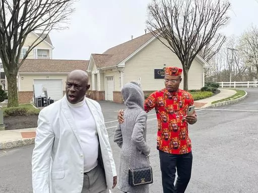 From left, Prince Dwumfour, Nicole Teliano and Peter Ezechukwu walk near the scene of the fatal shooting of their family member, Eunice Dwumfour, in Sayreville, N.J., April 5, 2023. Eunice Dwumfour, a Sayreville council member, was gunned down Feb. 1 as she arrived home in Sayreville. (AP Photo/Maryclaire Dale)