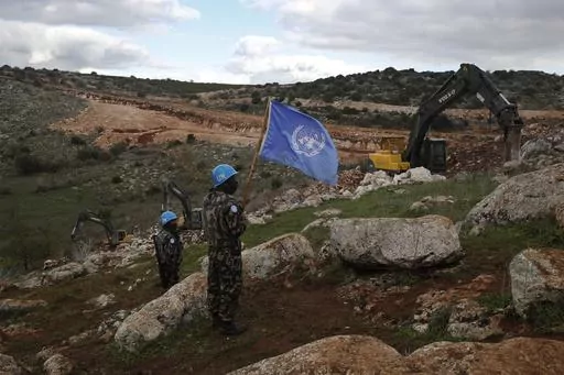 UN peacekeepers hold their flag, as they observe Israeli excavators attempt to destroy tunnels built by Hezbollah, near the southern Lebanese-Israeli border village of Mays al-Jabal, Lebanon on Dec. 13, 2019. Four United Nations military observers were wounded Saturday while patrolling along the southern Lebanese border after a shell exploded near them, the U.N. peacekeeping mission in southern Lebanon said. The military observers of the United Nations Truce Supervision Organization support the 