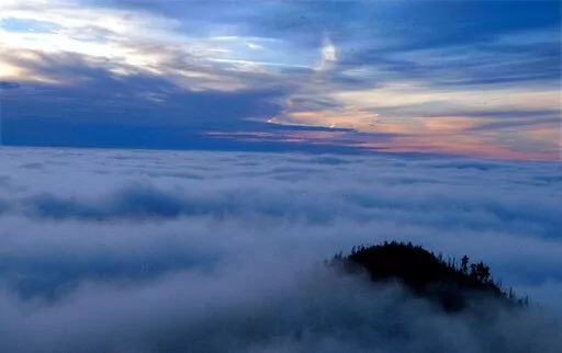 The sun sets over the Great Smoky Mountain National Park in this undated photo taken from the vantage point of Cliff Top near LeConte Lodge. Beginning March 2023, visitors to the national park will need to purchase a parking pass to use the facilities. (Joe Howell/Knoxville News Sentinel via AP, File)