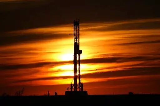 An oil drilling rig is pictured at sunset, Monday, March 7, 2022, in El Reno, Okla. A federal appeals court in New Orleans hears arguments Tuesday, May 10, 2022, about whether President Joe Biden legally suspended new oil and gas lease sales because of climate change worries. (AP Photo/Sue Ogrocki, File)