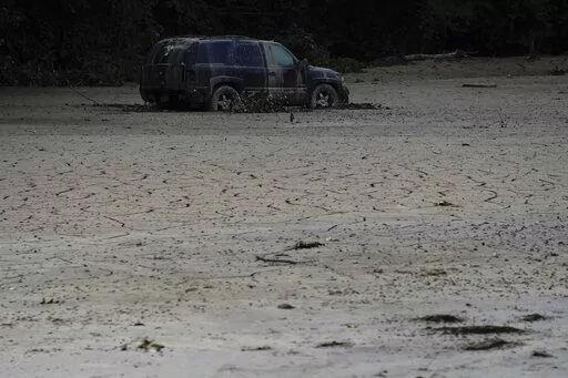 A vehicle is abandoned and surrounded by mud caused by massive flooding on Friday, Aug. 5, 2022, near Haddix, Ky. (AP Photo/Brynn Anderson)