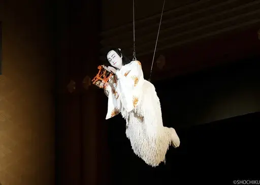 This photo provided by Shochiku shows Kabuki actor Danjuro Ichikawa playing a fox disguised as a warrior to follow Lady Shizuka, a court dancer, filying over the crowd in “Hoshiawase Jusandan” at the Kabukiza Theater in Tokyo, July 1, 2024. Danjuro is a virtuoso in switching roles. In his latest production, he plays 13 parts, including a beautiful princess, a sushi chef and the owner of the sushi restaurant, a brave samurai and a fox who impersonates that samurai to get close to the court da