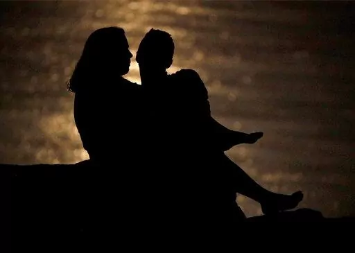 In this June 27, 2018, file photo a couple is silhouetted against moonlight reflecting off the Missouri River as they watch the full moon rise beyond downtown buildings in Kansas City, Mo. While money can be a source of stress in relationships, it can also spark romance if you use money dates to focus on your goals as a couple. First, consider your own goals and ask your partner about their values. Next, identify common goals, such as teaming up to vanquish debt or planning a vacation. Then sche