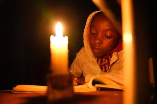 Tracy Carlos uses a candlelight to do her homework in Mabvuku on the outskirts of Harare on Wednesday, Aug, 3, 2022.Because of lengthy power cuts, the children do their homework by a candle, although their parents press them to use it sparingly. Her father Jeff Carlos says he gets about $100 dollars a month from his job as an overnight security guard for a church and the bar next door. Rising prices and a fast-depreciating currency have pushed many Zimbabweans to the brink, reminding people of w