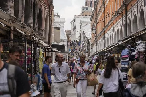 FILE -Tourists walk in a crowded street in Venice, Italy, Wednesday, Sept. 13, 2023. Venice on Saturday, Dec. 30, 2023 announced new limits on the size of tourist groups in another measure aimed at reducing the pressure of mass tourism on the famed canal city. Starting in June, groups will be limited to 25 people. (AP Photo/Luca Bruno, File)