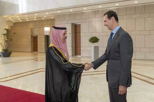 In this photo released by the Syrian official news agency SANA, Syrian President Bashar Assad, right, welcomes Saudi Minster of Foreign Affairs Faisal bin Farhan, left, before their meeting in Damascus, Syria, Tuesday, April 18, 2023. With momentum moving toward a likely readmission of Syria to the Arab League, Syrians in government-held areas are hoping that political normalization will ease an economic crisis and lead to foreign investment and better living conditions. (SANA via AP, File)