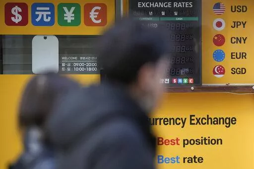 Pedestrians pass near a money exchange office in downtown Seoul, South Korea, Wednesday, Jan. 11, 2023. (AP Photo/Lee Jin-man)