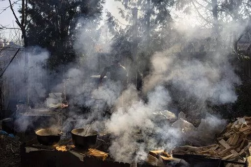 Volunteers cook in the courtyard of a theatre in the city of Drohobych, western Ukraine, Monday, March 21, 2022. The theatre has become a meeting point, where artists, including those displaced from other parts of Ukraine, have turned their talents to making food for soldiers and others as part of a massive volunteer war effort across the country. (AP Photo/Bernat Armangue)