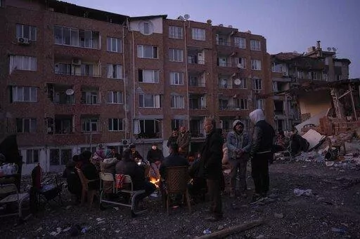 Friends and relatives of the Dagli family family gather around bonfires while rescue teams, search for family members under the rubble of a destroyed building in Antakya, southeastern Turkey, Wednesday, Feb. 15, 2023. Ever since the powerful 7.8 earthquake that has become Turkey's deadliest disaster in modern history, survivors have been gathering outside destroyed buildings, refusing to leave. (AP Photo/Bernat Armangue)