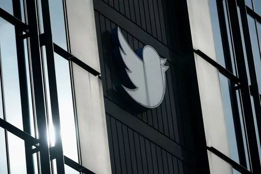 A Twitter logo hangs outside the company's offices in San Francisco, on Dec. 19, 2022. William Shatner, Monica Lewinsky and other prolific Twitter commentators — some household names, others little-known journalists — could soon be losing the blue check marks that helped verify their identity on the social media platform. (AP Photo/Jeff Chiu, File)