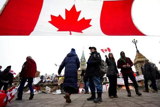 A Canada flag is hung between traffic light posts in front of Parliament Hill during a protest against COVID-19 restrictions in Ottawa, on Friday, Feb. 11, 2022.  Ontario’s premier declared a state of emergency Friday in reaction to the truck blockades in Ottawa and at the U.S. border and threatened heavy penalties against those who interfere with the free flow of goods and people. (Justin Tang /The Canadian Press via AP)