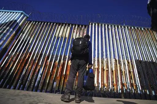 A migrant waits of the Mexican side of the border after United States Customs and Border Protection officers detained a couple of migrants crossing the US-Mexico border on the beach, in Tijuana, Mexico, Jan. 26, 2022. About 3 in 10 also worry that more immigration can cause native-born Americans to lose their economic, political and cultural influence, according to a poll by The Associated Press-NORC Center for Public Affairs Research. (AP Photo/Marco Ugarte, File)