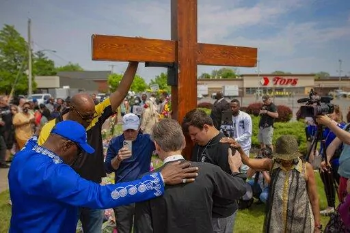A group prays at the site of a memorial for the victims of the Buffalo supermarket shooting outside the Tops Friendly Market on Saturday, May 21, 2022, in Buffalo, N.Y. Funeral services are set for Friday for three of those killed: Geraldine Talley, Andre Mackniel and Margus Morrison. They are among the 10 people killed and three wounded May 14 when a white gunman opened fire on shoppers and employees at a Tops Friendly Market. (AP Photo/Joshua Bessex, File)