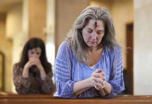 Dorsey Prince, right, and Shannon Carter pray during an Ash Wednesday Mass at St. John Neumann Catholic Church in Austin, Texas, Feb. 22, 2023. In 2024, Feb. 14 is a holiday heavyweight due to a calendar collision of events — it’s Valentine’s Day and Ash Wednesday. (Jay Janner/Austin American-Statesman via AP, File)