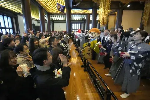 People try to catch lucky beans scattered by celebrities during the annual "Mame-maki," a ceremony marked in the hope of warding off evil spirits and inviting good luck, at the main hall of Zojoji Buddhist temple Tokyo Sunday, Feb. 2, 2025. (AP Photo/Eugene Hoshiko)