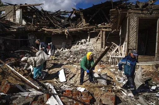 Local residents collect wood for heating from a destroyed school where Russian forces were based, in the recently retaken area of Izium, Ukraine, Monday, Sept. 19, 2022. Residents of Izium, a city recaptured in a recent Ukrainian counteroffensive that swept through the Kharkiv region, are emerging from the confusion and trauma of six months of Russian occupation, the brutality of which gained worldwide attention last week after the discovery of one of the world's largest mass grave sites.  (AP P