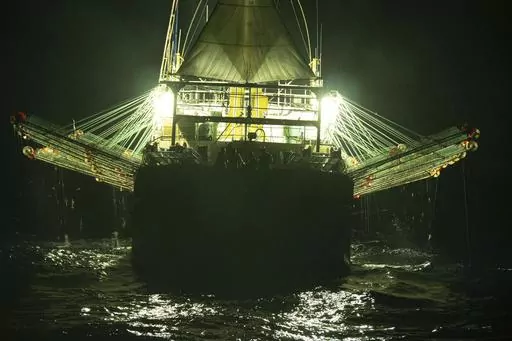 In this July 2021 photo provided by Sea Shepherd, the Chang Tai 802, a Chinese-flagged ship, fishes for squid at night on the high seas off the west coast of South America. Hazardous work conditions sometimes akin to slavery have been detected on nearly 500 industrial fishing vessels around the world, including this one, but identifying those responsible for abuses at sea is hampered by a lack of transparency and regulatory oversight, according to research by the Financial Transparency Coalition