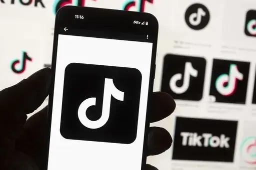 The TikTok logo is displayed on a mobile phone in front of a computer screen, Oct. 14, 2022, in Boston. TikTok is gearing up for a legal fight against a U.S. law that would force the social media platform to break ties with its China-based parent company or face a ban. A battle in the courts will almost certainly be backed by Chinese authorities as the bitter U.S.-China rivalry threatens the future of a wildly popular way for young Americans to connect online. (AP Photo/Michael Dwyer, File)