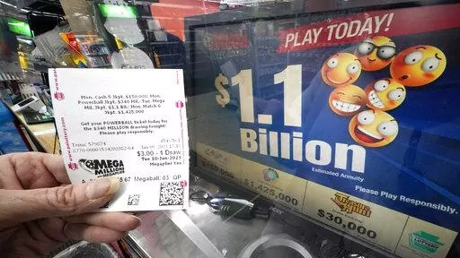 A Mega Millions customer displays her ticket for the estimated jackpot of $1.1 Billion at the Fuel On Convenience Store in Pittsburgh, Monday, Jan. 9, 2023. (AP Photo/Gene J. Puskar)