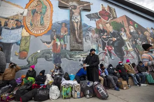 Migrants eat and wait for assistance while camping on a street in downtown El Paso, Texas, Sunday, Dec. 18, 2022. Christian voters and faith leaders have long been in the frontlines of providing assistance to migrants – but when it comes to support for immigration policies, from border security to legalization options for migrants already in the U.S., views diverge broadly. (AP Photo/Andres Leighton, File)