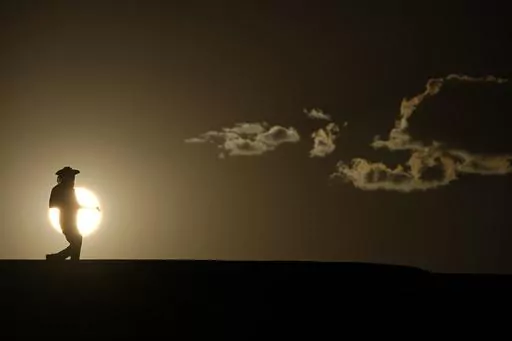 A person walks along a trail as the sun sets, Sunday, July 16, 2023, in Death Valley National Park, Calif. Human-caused global warming made July hotter for four out of five people on Earth, according to a new report issued Wednesday, Aug. 2, 2023, by Climate Central. (AP Photo/John Locher, File)