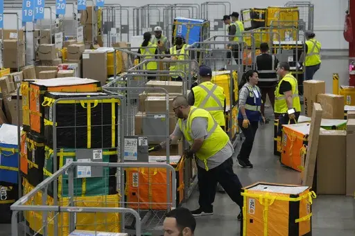 Amazon employees load packages on carts before being put on to trucks for distribution to customers for Amazon's annual Prime Day event at an Amazon's DAX7 delivery station on July 16, 2024, in South Gate, Calif. (AP Photo/Richard Vogel, File)