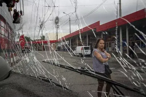 A woman looks at a trolleybus damaged by Russian shelling at Barabashovo market in Kharkiv, Ukraine, Thursday, July 21, 2022. (AP Photo/Evgeniy Maloletka)