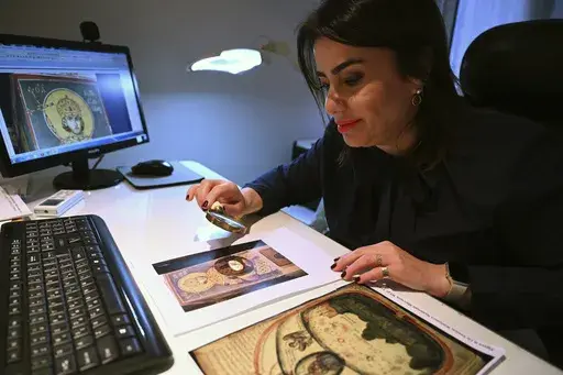 Christina Sotirakoglou a handwriting expert, observes Byzantine paintings based on photographs prints, at her office, in Thessaloniki, northern Greece, Saturday, Nov. 30, 2024. (AP Photo/Giannis Papanikos)