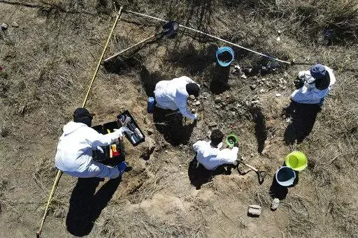 Forensic technicians excavate a field on a plot of land referred to as a cartel "extermination site" where burned human remains are buried, on the outskirts of Nuevo Laredo, Mexico, Tuesday, Feb. 8, 2022. The  insufficiency of investigations into Mexico’s nearly 100,000 disappearances is evident. There are 52,000 unidentified people in morgues and cemeteries, not counting places like this one, where the charred remains are measured only by weight. (AP Photo/Marco Ugarte)