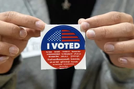 A election volunteer offers voters an "I Voted" sticker after casting their ballot on Super Tuesday, at the Ranchito Elementary School polling station in the Panorama City section of Los Angeles, Tuesday, March 5, 2024. Super Tuesday elections are being held in 16 states and one territory. Hundreds of delegates are at stake, the biggest haul for either party on a single day. (AP Photo/Richard Vogel)