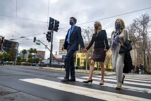 Former Theranos CEO Elizabeth Holmes, center, with her partner, Billy Evans, left, and mother, Noel Holmes, right, leaves federal court in San Jose, Calif., Thursday, Dec. 23, 2021. The jury began their third day of deliberations in her fraud and conspiracy trial on Thursday. (AP Photo/Nic Coury)