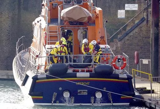 Members of the Dover lifeboat place a body bag on a stretcher after returning to the Port of Dover after a large search and rescue operation launched in the Channel off the coast of Dungeness, in Kent, Wednesday Dec. 14, 2022, following an incident involving a small boat likely to have been carrying migrants. Helicopters and lifeboats have been dispatched to the English Channel off the coast of Kent in southern England to rescue a small boat in distress, authorities said Wednesday. (Gareth Fulle