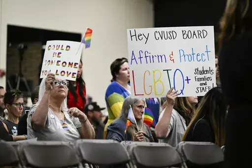 Parents, students, and staff of Chino Valley Unified School District hold up signs in favor of protecting LGBTQ+ policies at Don Antonio Lugo High School, in Chino, Calif., June 15, 2023. California Gov. Gavin Newsom signed a law Monday, July 15, 2024, barring school districts from passing policies that require schools to notify parents if their child asks to change their gender identification. (Anjali Sharif-Paul/The Orange County Register via AP, File)