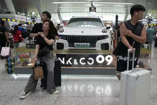 Passengers wait near a hybrid luxury SUV from China automaker Lynk&co displayed at the train station in Hangzhou in eastern China's Zhejiang province on Monday, July 3, 2023. Chinese automakers are winning over drivers as they make major inroads into Europe’s electric vehicle market, challenging long-established homegrown brands in an industry that’s key to the continent’s green energy transition. The European Union has launched an investigation into Beijing’s support for its EV industry