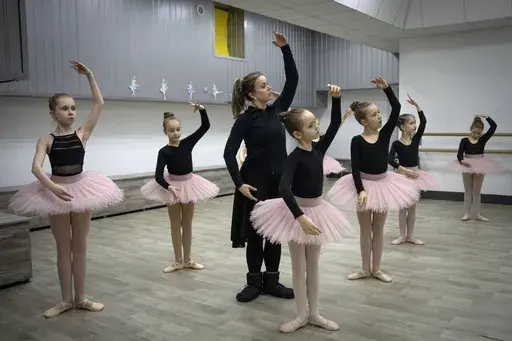 A ballet coach teaches girls in a ballet studio in a bomb shelter in Kharkiv, Ukraine, Monday, March 18, 2024. In northeast Ukraine, a dance studio that doubles as a bomb shelter is an escape from the horrors of war for about 20 young girls. The Princess Ballet Studio in Kharkiv is a spartan, windowless room, but practicing underground means they can dance through the almost hourly air raid alerts. (AP Photo/Efrem Lukatsky)