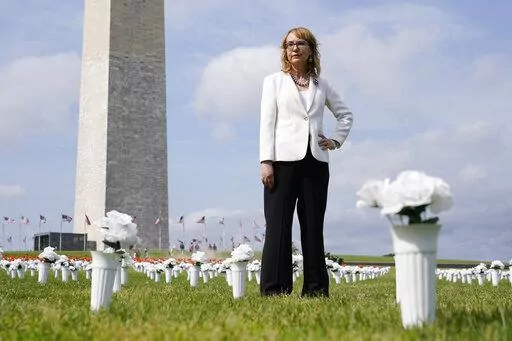 Former congresswoman and gun violence survivor Gabby Giffords stands among vases of flowers that make up the Gun Violence Memorial installation near the Washington Monument on the National Mall in Washington, Tuesday, June 7, 2022. The flowers are meant to represent the number of Americans who die from gun violence each year. (AP Photo/Patrick Semansky)