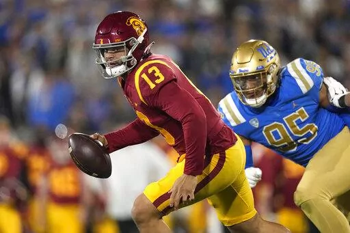Southern California quarterback Caleb Williams, left, runs with the ball while being chased by UCLA defensive lineman Sitiveni Havili-Kaufusi during the first half of an NCAA college football game Saturday, Nov. 19, 2022, in Pasadena, Calif. (AP Photo/Mark J. Terrill)