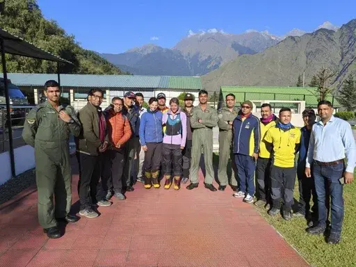 This photograph shared by Indian Air Force on the X platform shows two foreign climbers, center, who were stranded in India's Himalayas posing with Indian Air Force personnel who rescued them in Uttarakhand, India, Monday, Oct. 7, 2024. (Indian Air Force on X via AP)